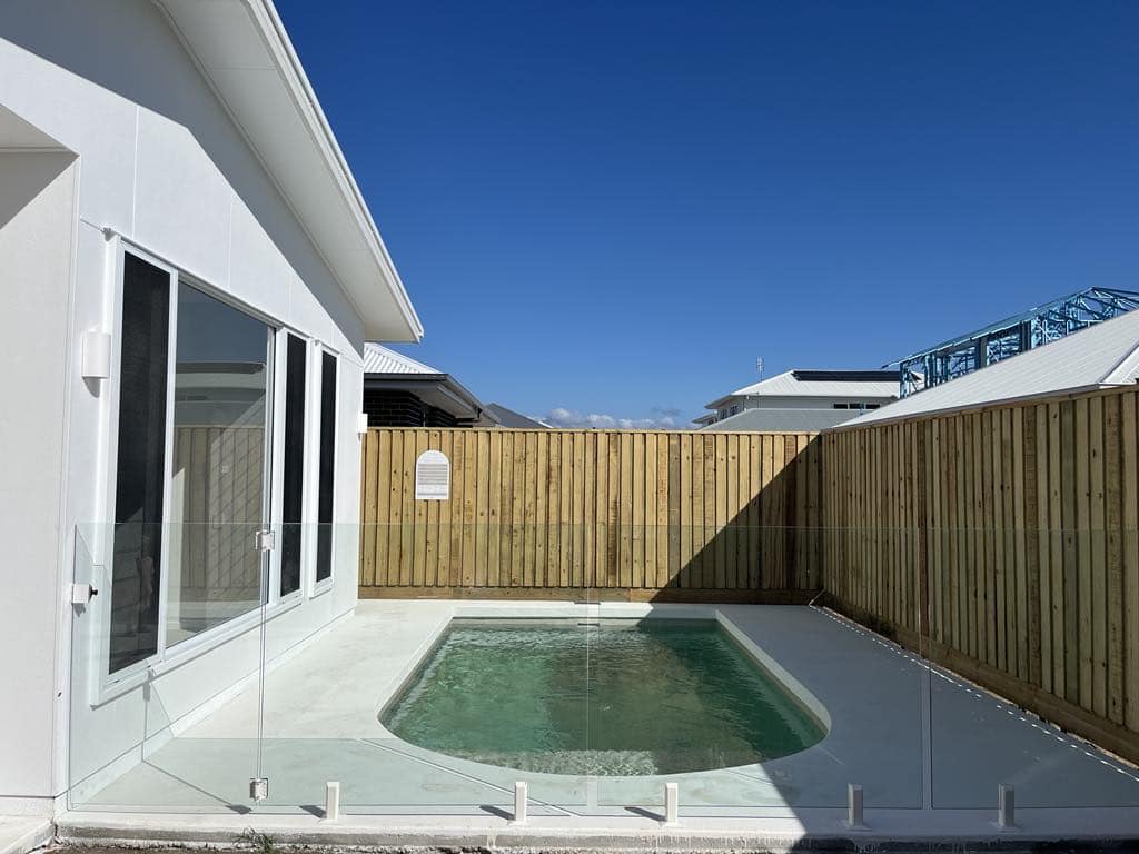 Frameless glass with white spigots and a glass gate around a plunge pool